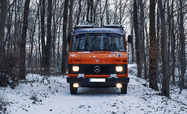 Met de bus recht het winterwonderland in: Met de juiste voorbereiding een geweldig avontuur. Rode camper in besneeuwd landschap