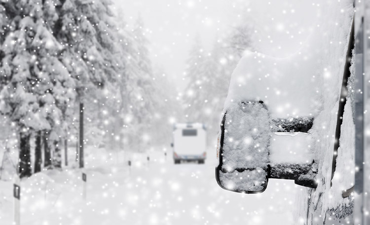 Om ervoor te zorgen dat jouw camper veilig van A naar B komt, moet hij winterklaar zijn. Close-up van een besneeuwde buitenspiegel van een camper in een besneeuwd landschap.